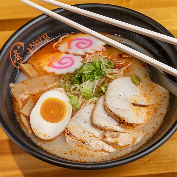 A bowl of Nara Sushi Ramen's spicy ramen with pork, egg, bamboo shoots, and narutomaki.