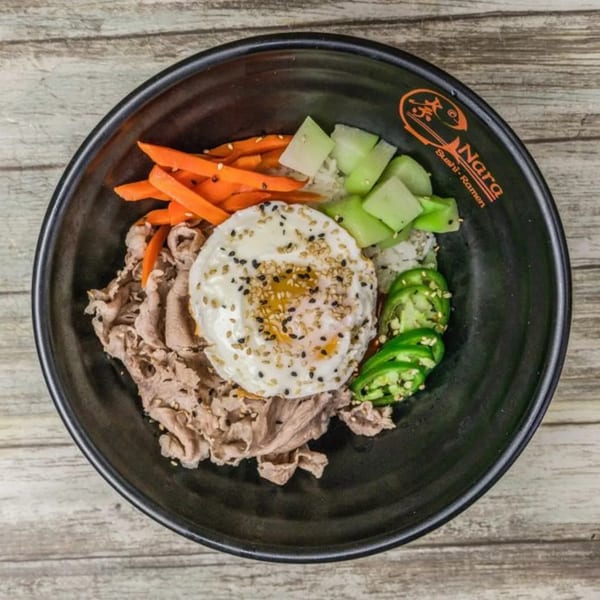 A Nara Sushi Ramen bowl with beef, fried egg, carrots, cucumbers, and jalapeños.